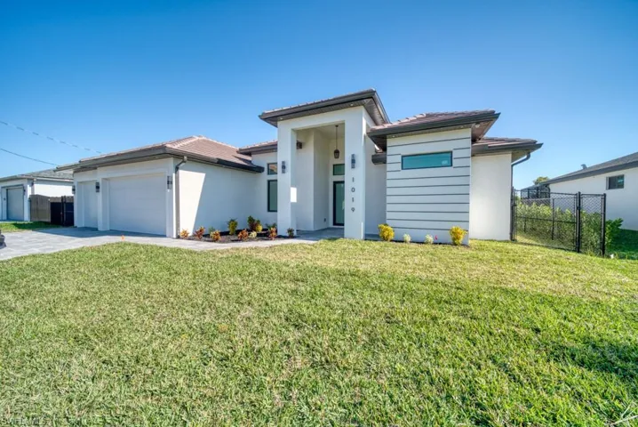 Prairie-style home featuring a garage, stucco siding, and driveway