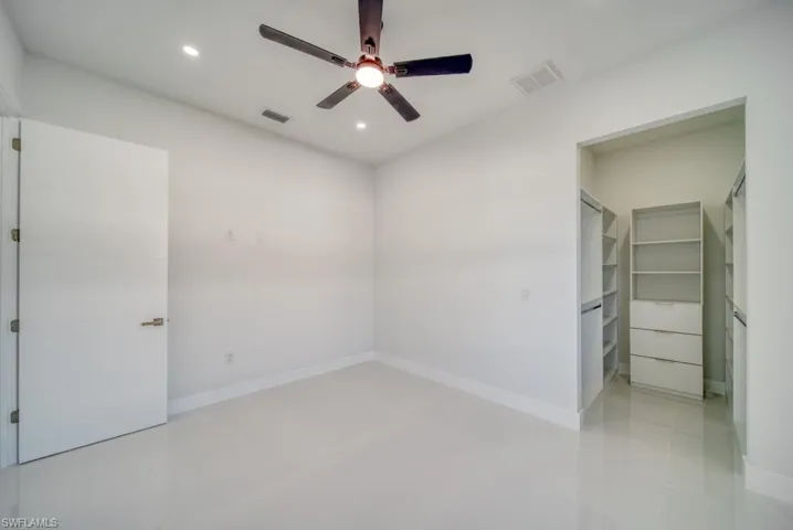 Unfurnished bedroom featuring a walk in closet, a ceiling fan, and recessed lighting