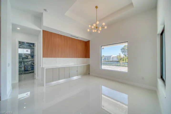 Unfurnished dining area with a chandelier, tile patterned flooring, and a raised ceiling
