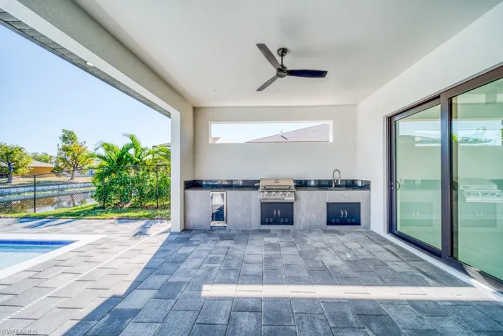 View of patio featuring an outdoor kitchen, a ceiling fan, and an outdoor pool