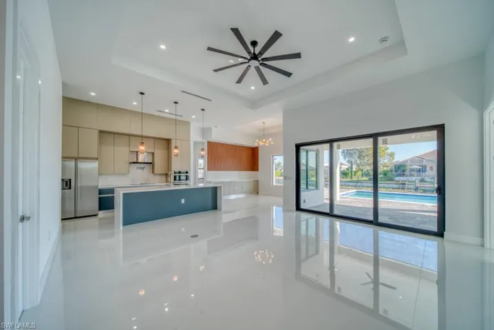 Kitchen featuring modern cabinets, a spacious island, a tray ceiling, a chandelier, and stainless steel fridge