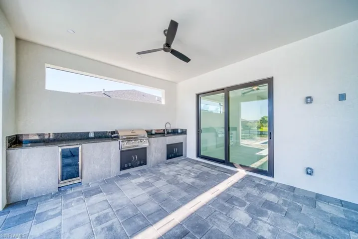 View of patio with exterior kitchen, beverage cooler, and a ceiling fan