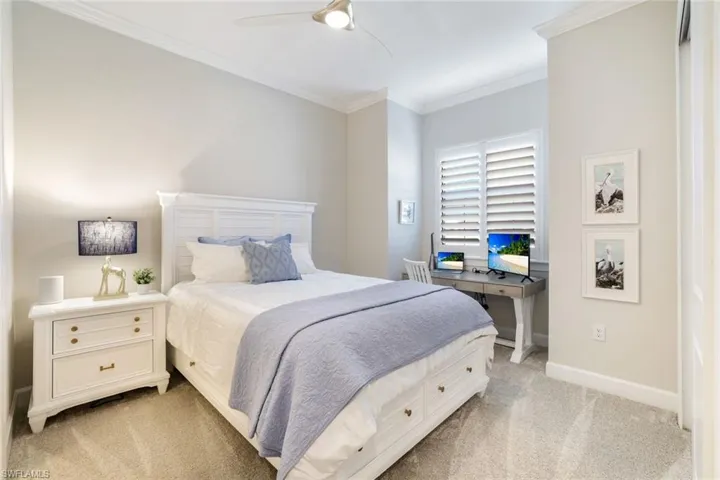 Recessed window with plantation shutters, crown molding, ceiling fan, and light-colored carpeting