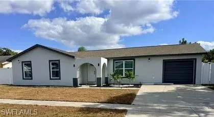 Stucco exterior with a shingle roof, arched entryway, and an attached garage with a dark panel door
