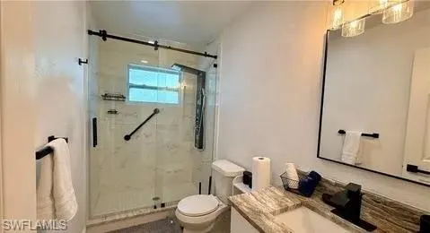 Glass-enclosed shower with a sliding barn door style entry, black fixtures, and a white tile surround