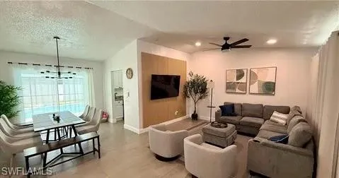 Open-concept living and dining area featuring tile flooring, a contemporary ceiling fan, recessed lighting, and a prominent wood-panel accent wall