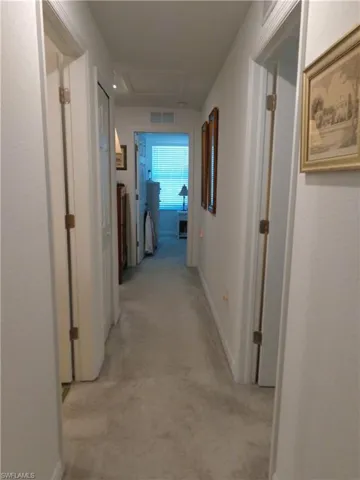 Corridor featuring baseboards and light carpet