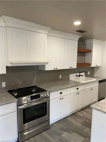 Kitchen featuring tasteful backsplash, sink, dishwasher, range, and white cabinetry