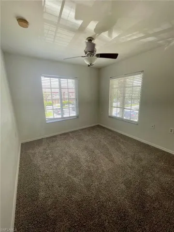 Carpeted empty room featuring a ceiling fan and a smoke detector