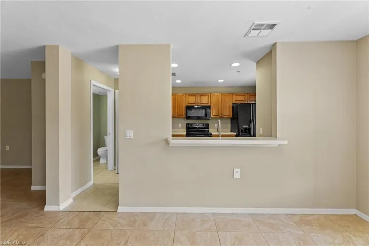 Kitchen featuring black appliances, light countertops, light tile patterned floors, recessed lighting, and brown cabinets