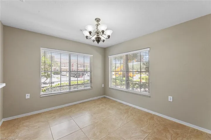 Empty room with a chandelier and light tile patterned floors