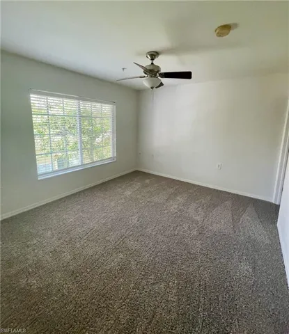 Carpeted empty room with a smoke detector and ceiling fan