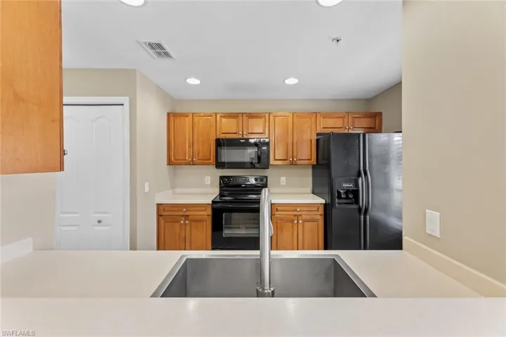 Kitchen featuring black appliances, light countertops, recessed lighting, and brown cabinets