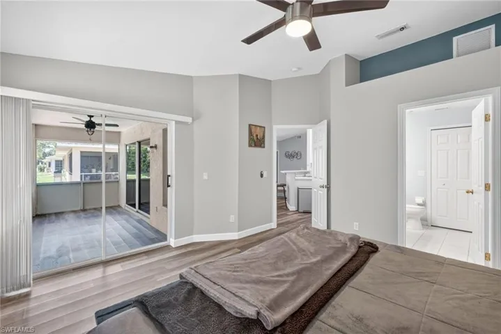 Vaulted ceilings featuring a central ceiling fan, wood-finish flooring, sliding glass doors, and a double-door entryway