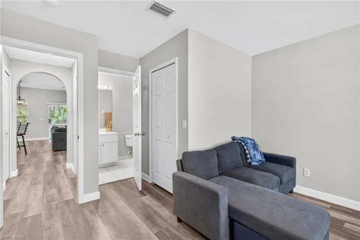 Wood-finish flooring throughout, arched doorway, and built-in closet with six-panel door