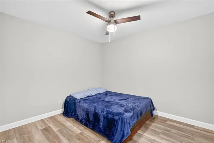 Neutral-toned interior space featuring wood-finish flooring and a central ceiling fan with integrated lighting