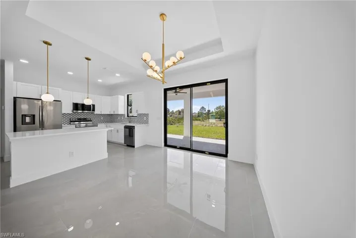 Kitchen featuring white cabinets, a chandelier, stainless steel appliances, backsplash, and a kitchen island