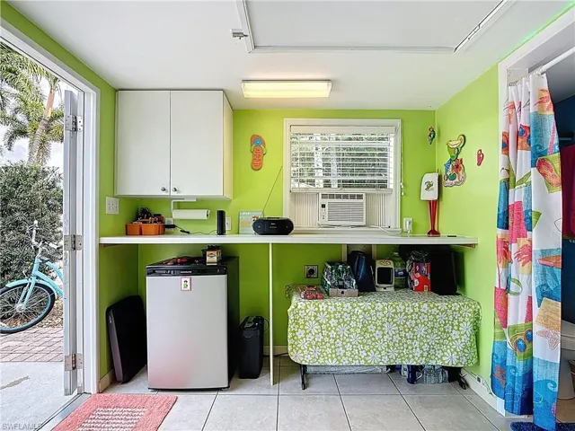 Kitchen featuring white cabinets, fridge, light tile patterned flooring, and light countertops