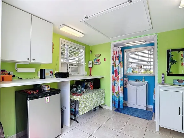 Kitchen with white cabinets, fridge, light countertops, light tile patterned floors, and cooling unit