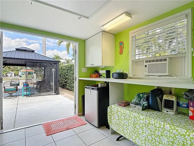 Kitchen with plenty of natural light, white cabinetry, freestanding refrigerator, and light tile patterned floors