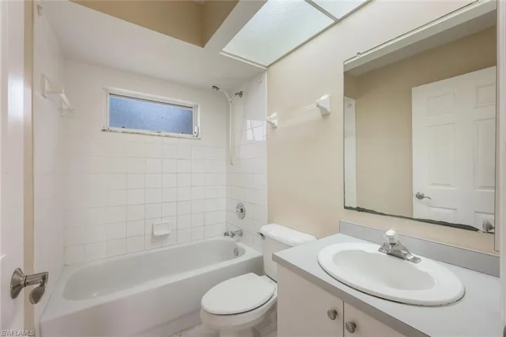 Full bathroom featuring tiled shower / bath combo, vanity, and toilet