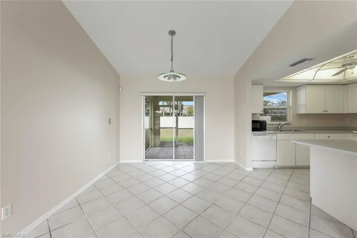 Unfurnished dining area with light tile patterned floors, vaulted ceiling, and sink