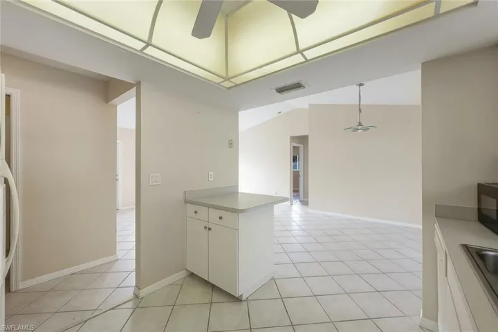 Kitchen with kitchen peninsula, light tile patterned flooring, pendant lighting, and white cabinets
