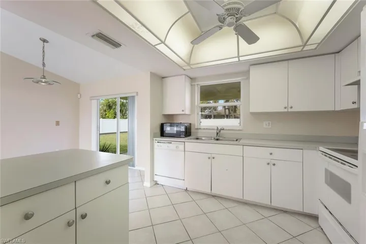 Kitchen featuring sink, white cabinets, and white appliances
