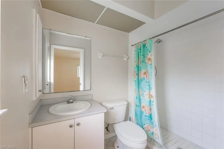 Bathroom with toilet, a shower with shower curtain, tile patterned flooring, and vanity