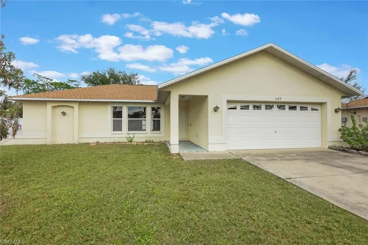 Ranch-style home featuring a garage and a front lawn