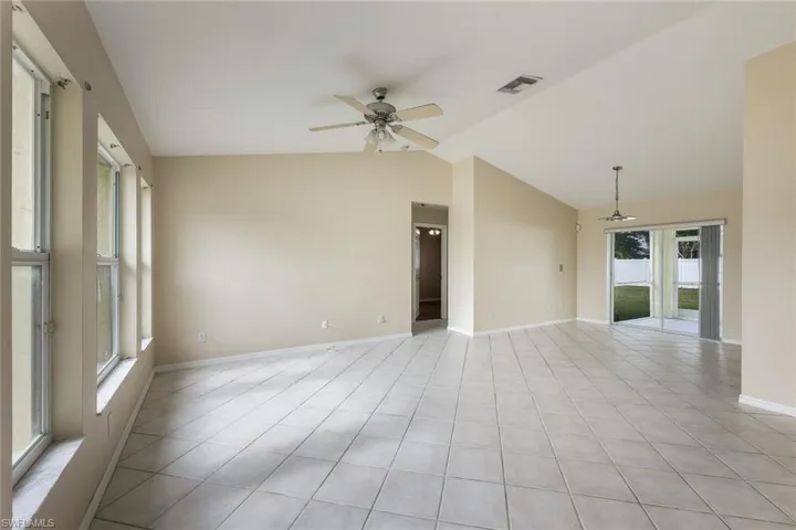 Tiled empty room with ceiling fan and lofted ceiling