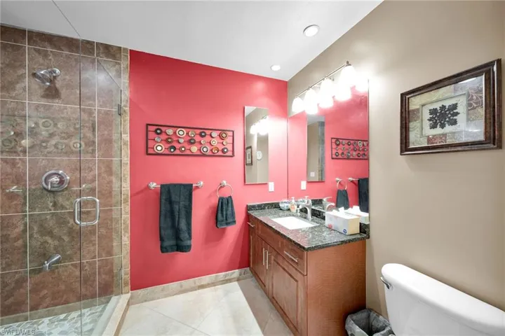 Bathroom featuring a shower with shower door, vanity, tile patterned floors, and toilet