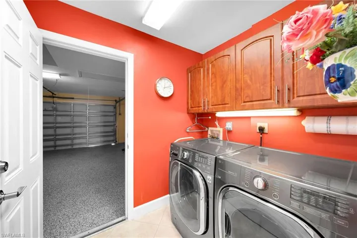 Laundry area featuring cabinets, washing machine and dryer, and light tile patterned floors