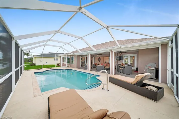 View of swimming pool featuring glass enclosure, a patio area, and ceiling fan