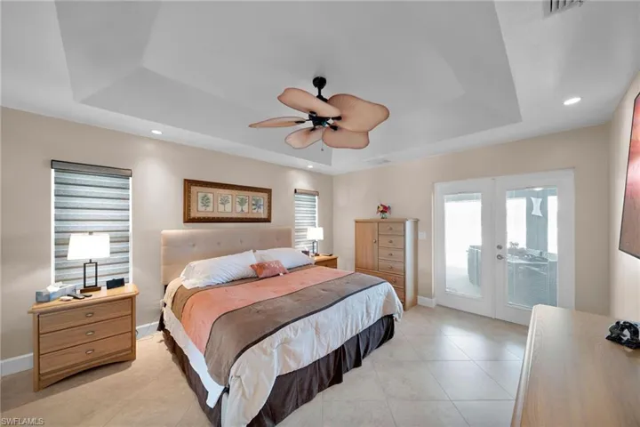 Bedroom featuring ceiling fan, access to outside, french doors, and a tray ceiling