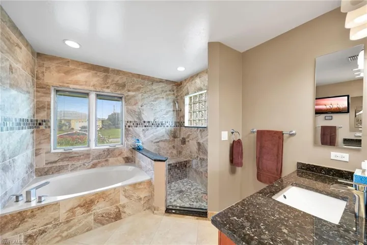 Bathroom featuring independent shower and bath, vanity, and tile patterned floors