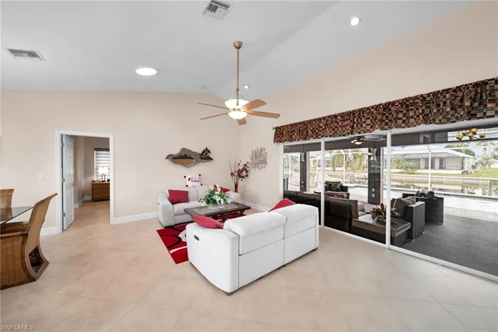 Living room with high vaulted ceiling, light tile patterned floors, and ceiling fan