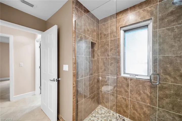 Bathroom with tile patterned flooring, a healthy amount of sunlight, and an enclosed shower