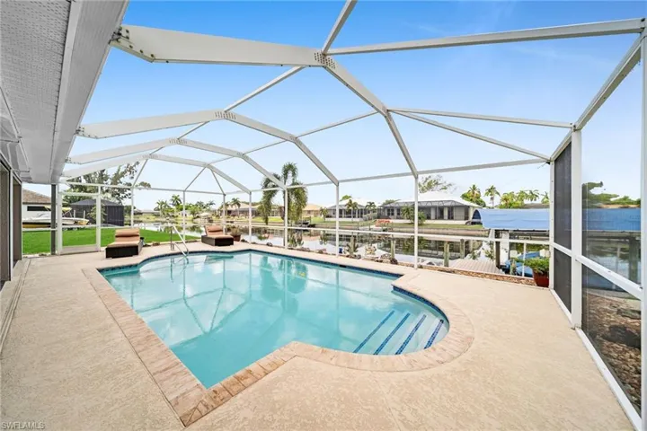 View of swimming pool with a patio area and glass enclosure