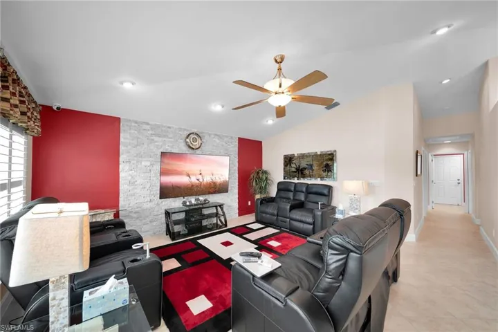 Tiled living room with lofted ceiling and ceiling fan
