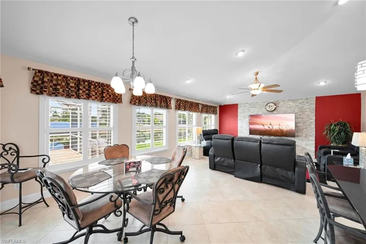Tiled dining room featuring ceiling fan with notable chandelier