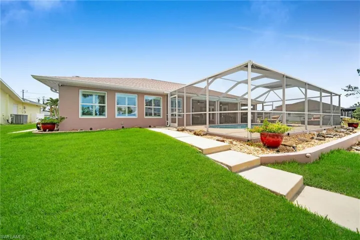 Rear view of property with cooling unit, a lawn, and glass enclosure