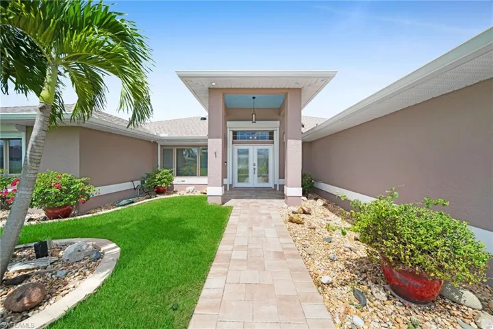 View of exterior entry featuring french doors and a lawn