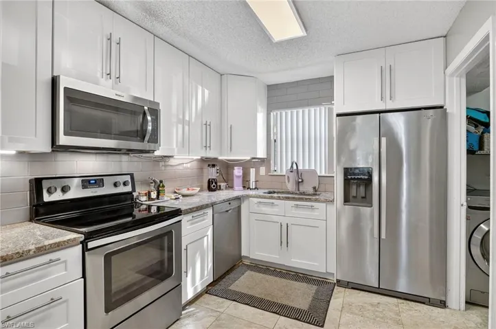Kitchen with appliances with stainless steel finishes, white cabinetry, and a textured ceiling