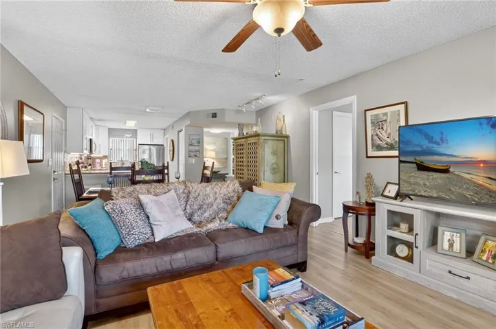 Living area with a textured ceiling, ceiling fan, and wood finished floors