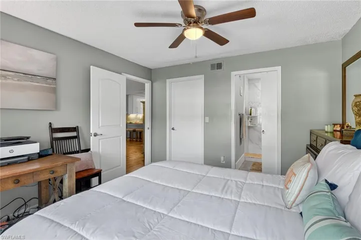 Bedroom with a textured ceiling, a ceiling fan, connected bathroom, and wood finished floors