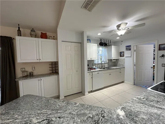 Kitchen featuring light tile patterned flooring, granite counter tops, desk top area & pantry
