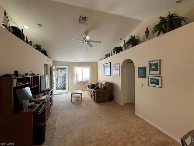 Living room featuring front screen door, light colored carpet, and plant shelves located on both sides of the living area