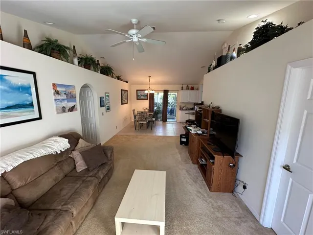 Carpeted living room with vaulted ceiling and ceiling fan