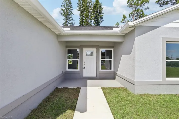 Doorway to property featuring a lawn